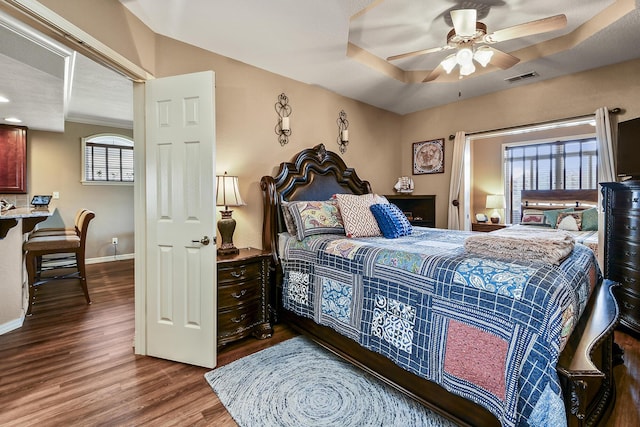 bedroom with a ceiling fan, visible vents, wood finished floors, and baseboards