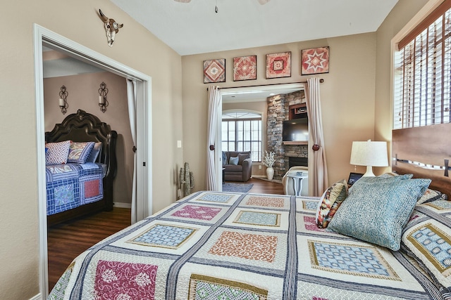 bedroom with a fireplace, baseboards, and wood finished floors