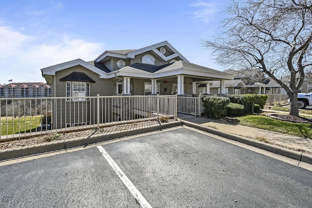 bungalow featuring a porch, fence, and uncovered parking