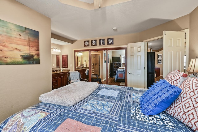 bedroom with wood finished floors, a closet, ensuite bathroom, and a sink