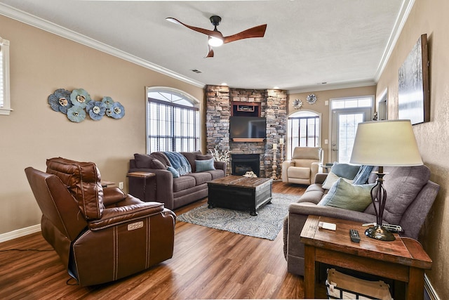 living room with a wealth of natural light, wood finished floors, a fireplace, and ornamental molding