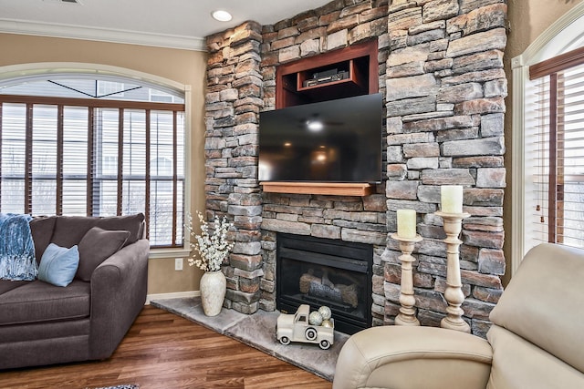 living room featuring visible vents, baseboards, ornamental molding, a fireplace, and wood finished floors