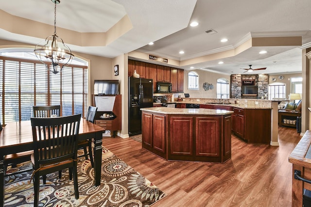 kitchen with black appliances, visible vents, a tray ceiling, and a center island