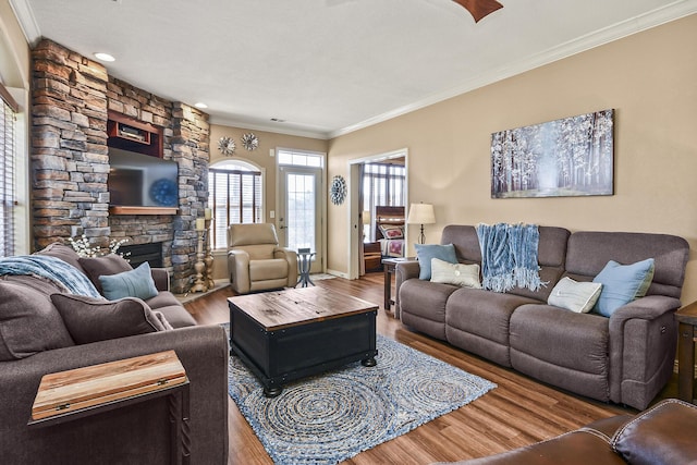 living area with a fireplace, crown molding, and wood finished floors