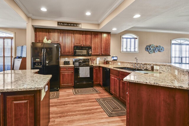 kitchen featuring a peninsula, plenty of natural light, a sink, black appliances, and crown molding