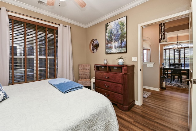 bedroom featuring visible vents, dark wood-type flooring, baseboards, ornamental molding, and ceiling fan with notable chandelier