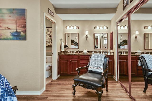 bathroom featuring a sink, toilet, wood finished floors, and double vanity