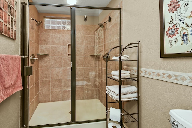 bathroom featuring a shower stall, toilet, and a textured wall