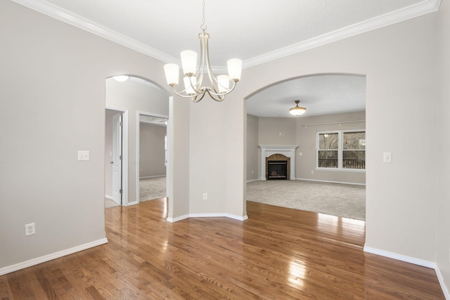 interior space featuring arched walkways, a fireplace, baseboards, and wood finished floors