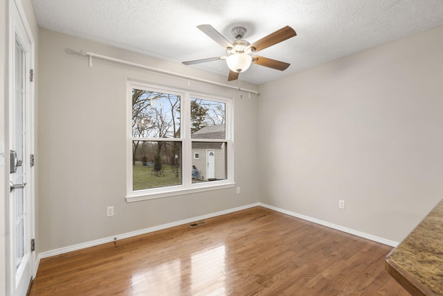 unfurnished room with baseboards, a textured ceiling, and wood finished floors