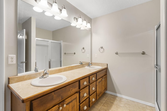 bathroom with a sink, double vanity, a shower stall, and tile patterned flooring