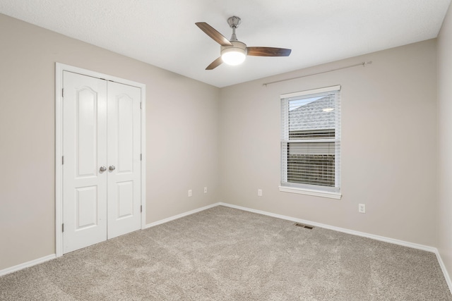 unfurnished bedroom with a ceiling fan, baseboards, visible vents, carpet floors, and a closet