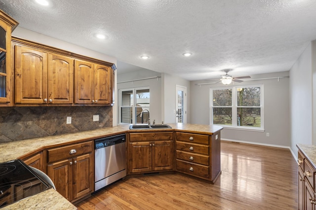 kitchen featuring a sink, stainless steel dishwasher, a peninsula, and light countertops