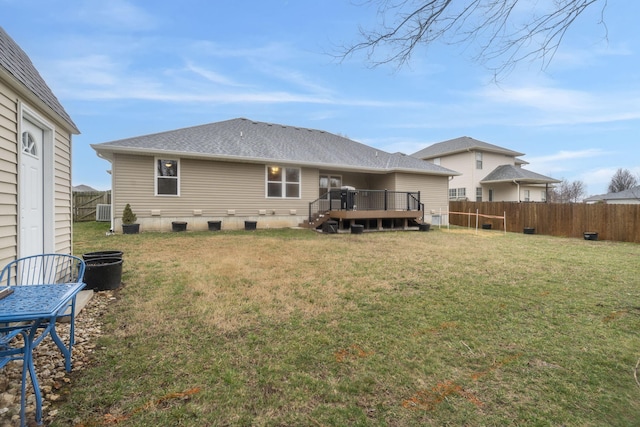 back of house with a deck, a fenced backyard, a lawn, and roof with shingles