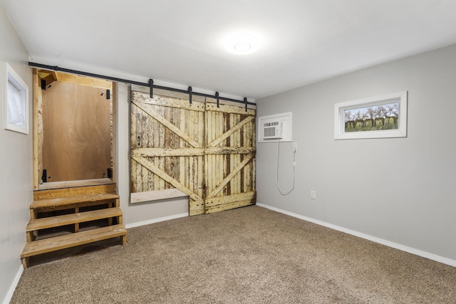 below grade area with a barn door, baseboards, and carpet floors