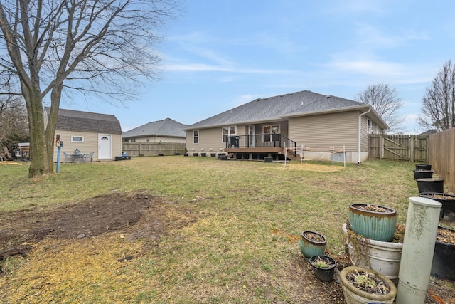 rear view of property featuring a yard, a fenced backyard, an outdoor structure, a storage unit, and a deck