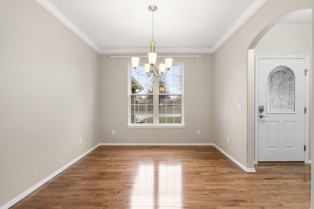 foyer with a chandelier, baseboards, wood finished floors, and crown molding