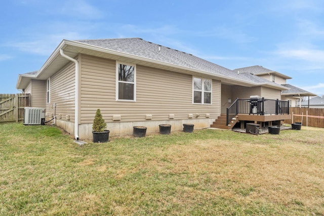 back of house featuring central AC unit, a lawn, a wooden deck, and fence