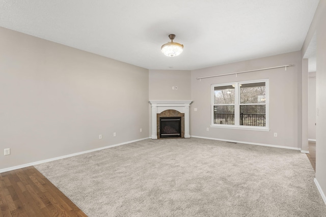 unfurnished living room with baseboards, wood finished floors, and a tile fireplace