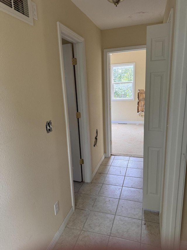 corridor with light tile patterned floors, visible vents, and baseboards