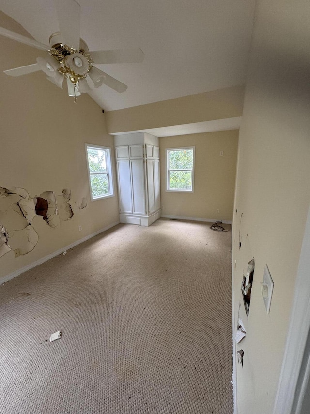 interior space featuring carpet flooring, ceiling fan, baseboards, and vaulted ceiling