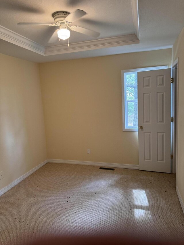 foyer entrance featuring light carpet, a raised ceiling, ornamental molding, a ceiling fan, and baseboards