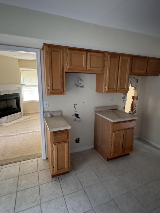 kitchen with light countertops, brown cabinetry, and a tile fireplace