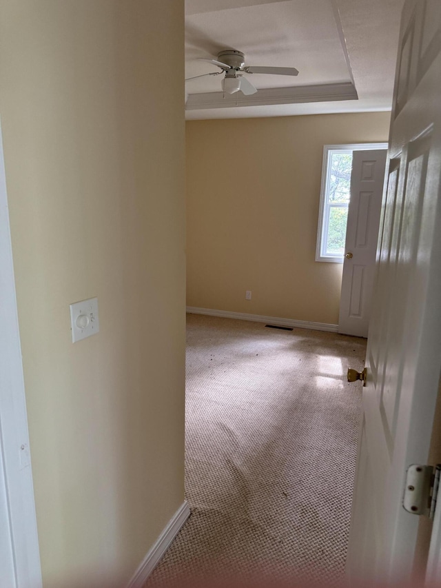 carpeted spare room with ceiling fan, a tray ceiling, and baseboards