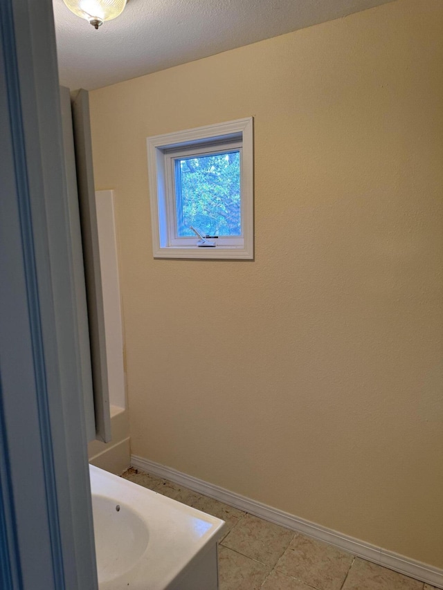 bathroom with tile patterned floors, baseboards, and a textured ceiling