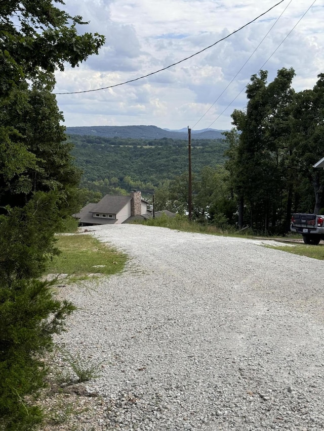 exterior space with a forest view, a mountain view, and gravel driveway