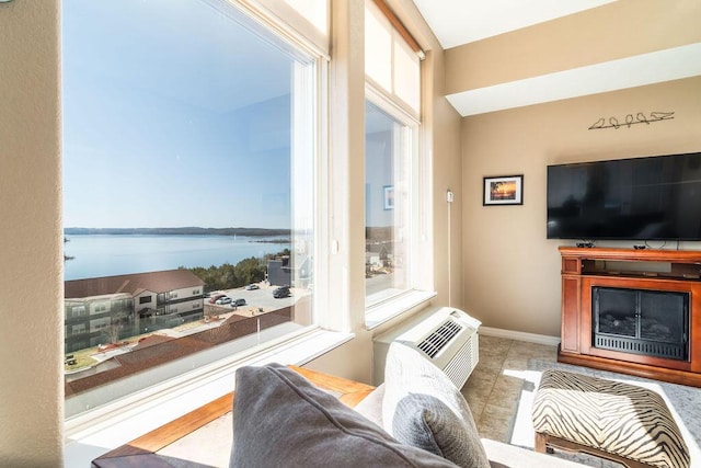 living area featuring a wealth of natural light, a fireplace, a wall mounted air conditioner, and baseboards