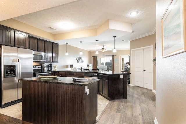 kitchen featuring visible vents, dark brown cabinets, a kitchen island, appliances with stainless steel finishes, and a peninsula