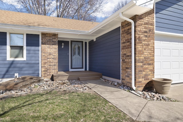 property entrance with brick siding, an attached garage, and a shingled roof