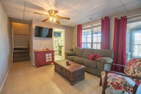 living room featuring stairs, a ceiling fan, baseboards, and a drop ceiling