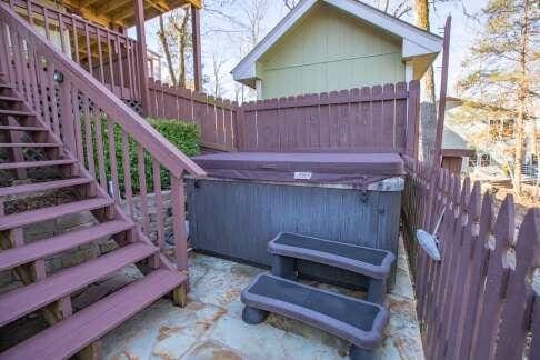 view of patio featuring stairway, fence, and a hot tub