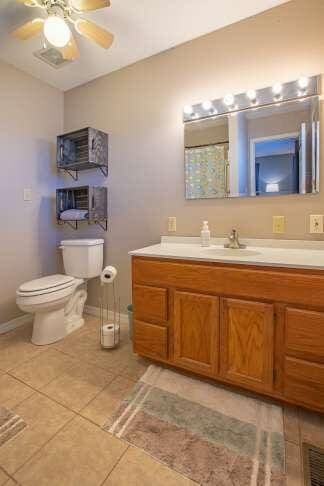 bathroom with vanity, a ceiling fan, baseboards, tile patterned flooring, and toilet