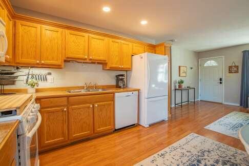 kitchen featuring light countertops, recessed lighting, light wood-style floors, white appliances, and a sink