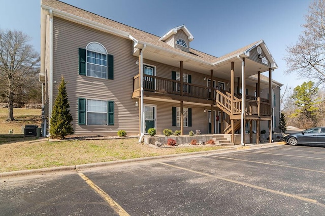 exterior space with central AC unit, stairs, a yard, and uncovered parking