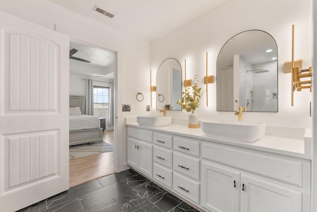 ensuite bathroom featuring double vanity, visible vents, marble finish floor, and a sink