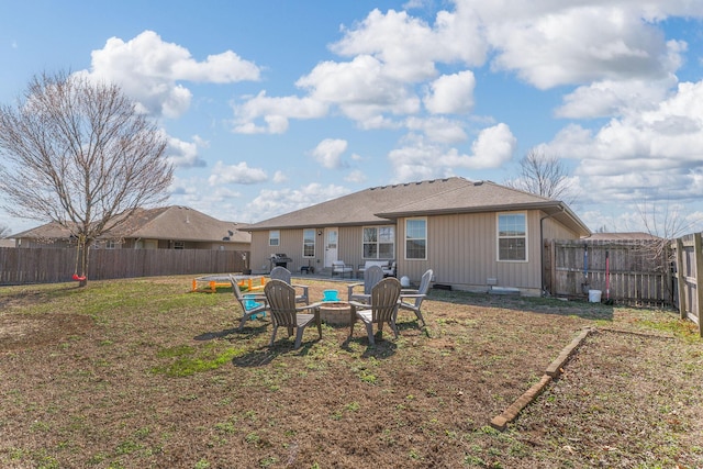 rear view of house featuring a fire pit, a fenced backyard, and a lawn