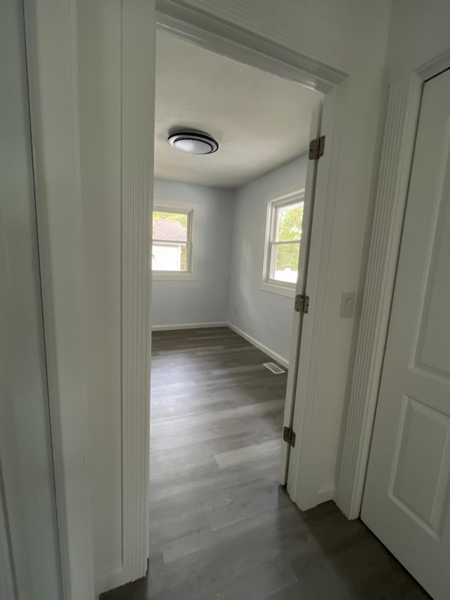 hallway with a wealth of natural light, baseboards, and wood finished floors