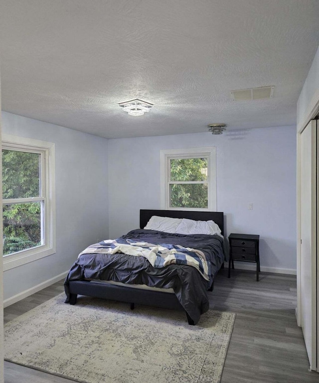 bedroom with multiple windows, wood finished floors, and visible vents