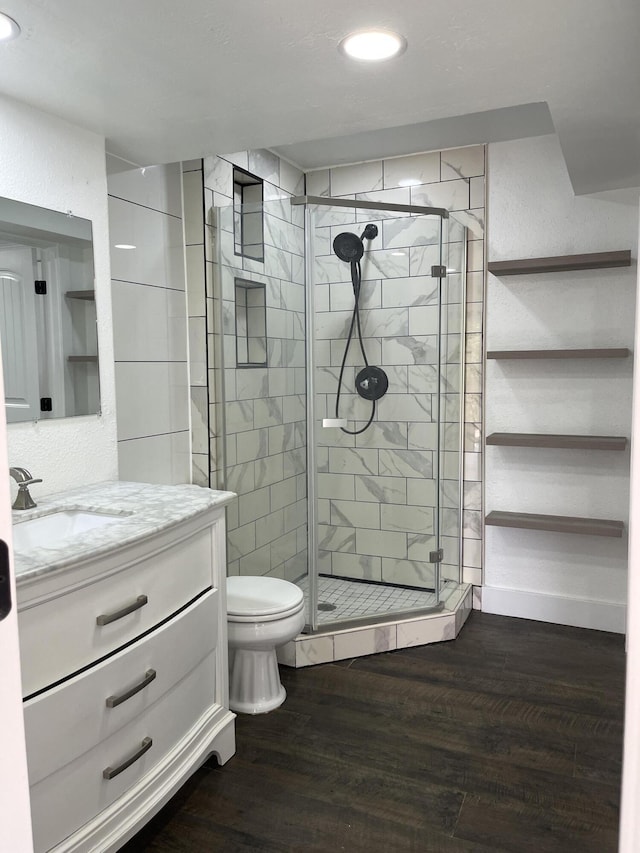 bathroom featuring toilet, wood finished floors, recessed lighting, a shower stall, and vanity