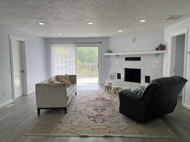 living room with visible vents, baseboards, wood finished floors, and a fireplace