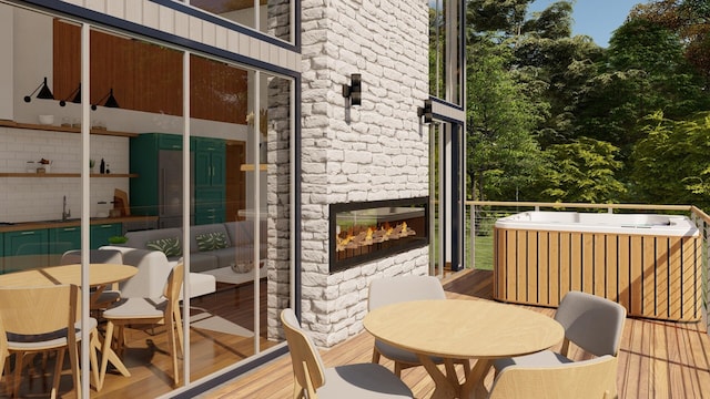 wooden terrace with a stone fireplace, outdoor dining area, and a sink