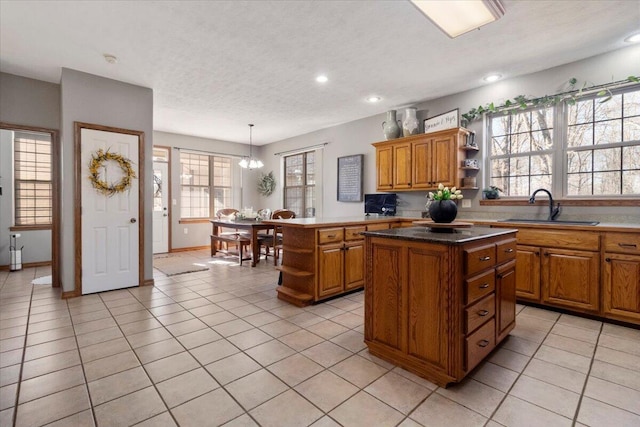 kitchen with open shelves, a sink, a center island, brown cabinetry, and light tile patterned floors