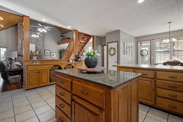 kitchen featuring light tile patterned floors, brown cabinets, a center island, and lofted ceiling