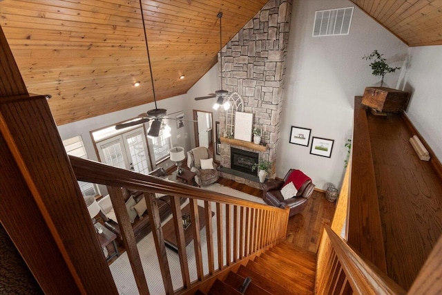 staircase featuring wood finished floors, visible vents, high vaulted ceiling, a fireplace, and wooden ceiling