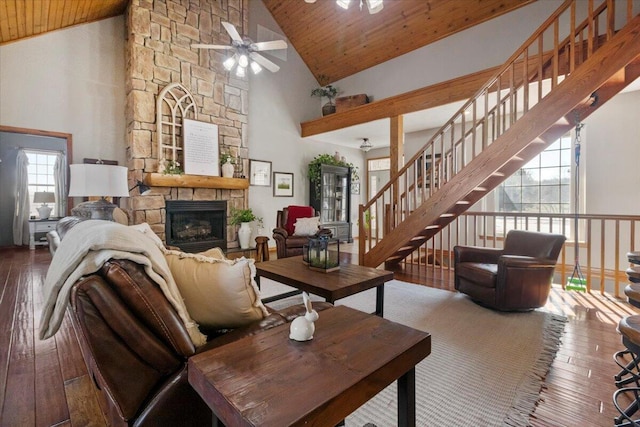 living area featuring a stone fireplace, wood ceiling, ceiling fan, and hardwood / wood-style flooring