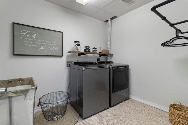 clothes washing area featuring laundry area, washing machine and dryer, visible vents, and baseboards